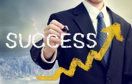 Businessman writing success with rising arrows above the cityの写真素材