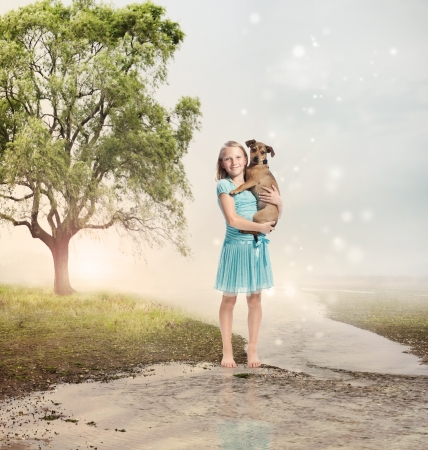Young Blonde Girl Holding her Puppy at a Magical Brookの写真素材
