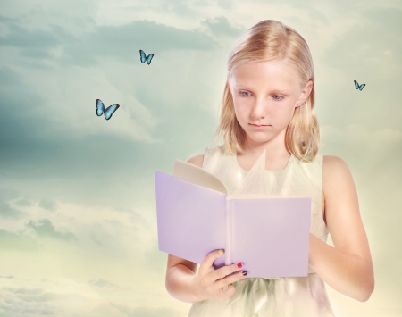 Little Blonde Girl Reading a Book with Butterfliesの写真素材