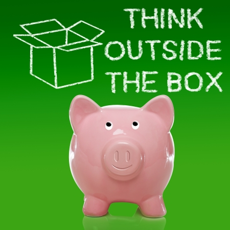 Smiling Piggy bank with thinking outside the box on green backgroundの写真素材