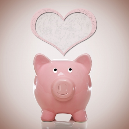 Happy piggy bank with pink heart on pink backgroundの写真素材