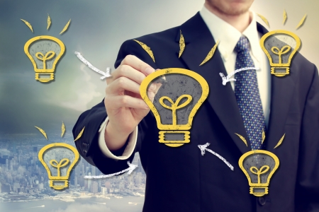 Businessman with light bulbs on a city backdropの写真素材