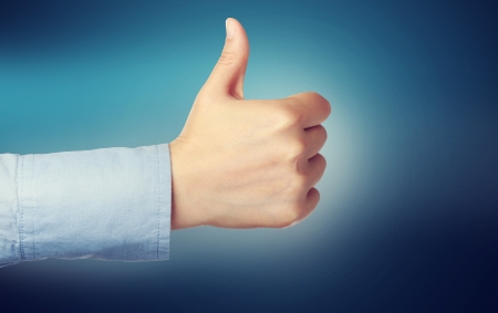 Person giving the thumbs up over blue backgroundの写真素材