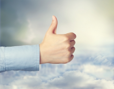 Person giving the thumbs up over cloudscapeの写真素材