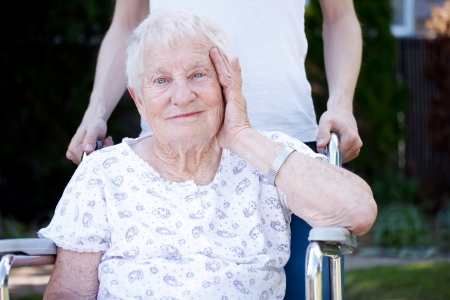 Happy senior lady in wheelchair with caregiverの写真素材