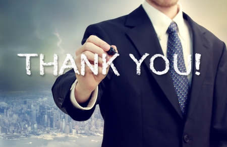 Business man drawing THANK YOU on a big city backgroundの写真素材