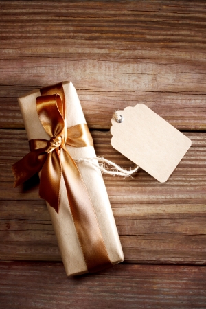 Brown rectangular present box on a rustic wood table with a bow and a blank labelの写真素材