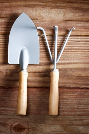 Gardening tools -  a shovel and a rake on a rustic wooden table の写真素材