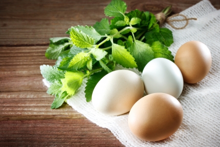 Eggs on a rustic table of wood with a sprig of mintの写真素材