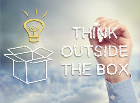 Think outside the box concept with idea lightbulb and open box drawing in chalkの写真素材