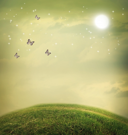 Butterflies in the fantasy hilltop landscape with moonの写真素材