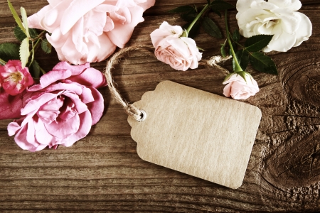 Handmade paper tag with string and roses on a rustic wooden tableの写真素材