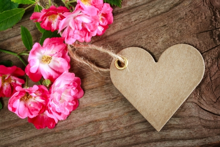 Handmade heart shaped tag with robin hood roses on a rustic wooden table の写真素材