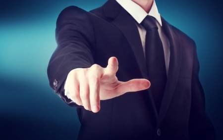 Business man with pointing to something or touching a touch screen on blue backgroundの写真素材
