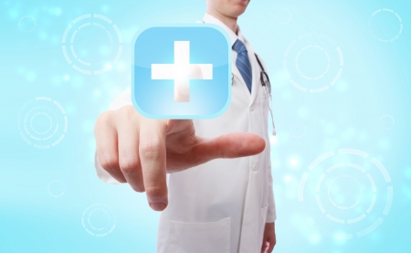 Medical doctor pushing a blue and white medical cross icon over light blue backgroundの写真素材