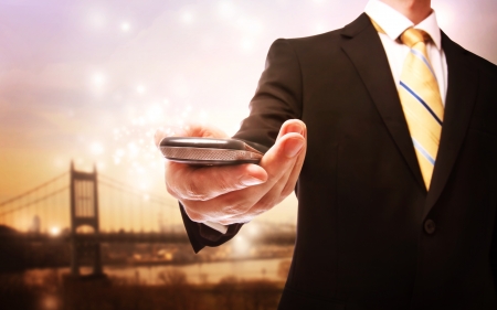 Business man with mobile phone on a scenic bridge in the backgroundの写真素材