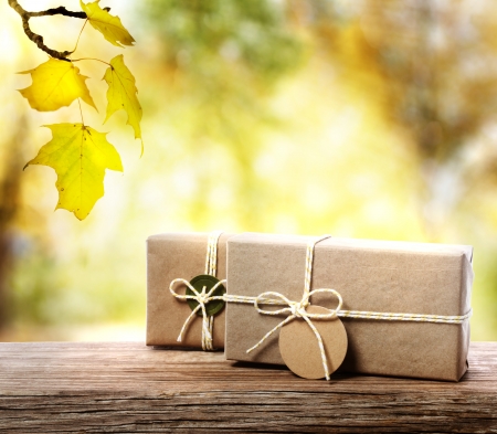 Handcrafted gift boxes on aged  wooden boards with an autumn foliage の写真素材