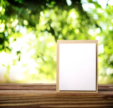 Greeting card on the wooden table over green tree leavesの写真素材