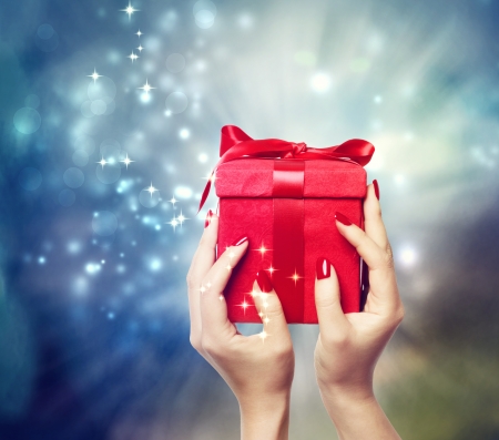 Red present box on Christmas on shinning being held up by in a woman's handsの写真素材