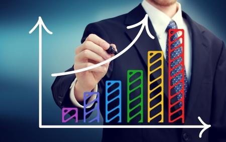 Businessman drawing a rising arrow over the colorful bar graphの写真素材