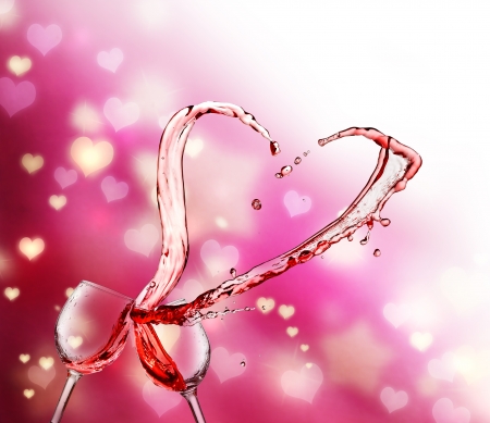 Heart splash from two glasses of red wine on abstract small heart lights backgroundの写真素材