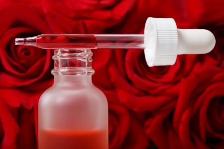 Dropper and essential oil with red rosesの写真素材