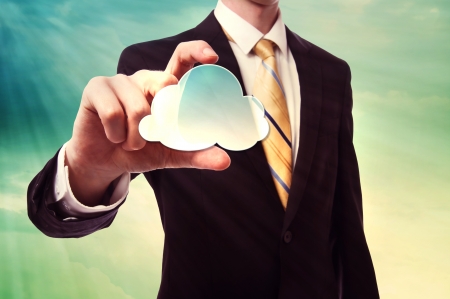 Businessman holding a cloud computing icon over cloudscape backgroundの写真素材