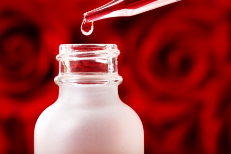Dropper bottle with rose essence over beautiful red rosesの写真素材