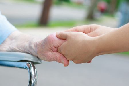 Caregiver holding an elderly womans hand outsideの写真素材