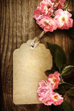 Handmade tag with robin hood roses on a rustic wooden tableの写真素材