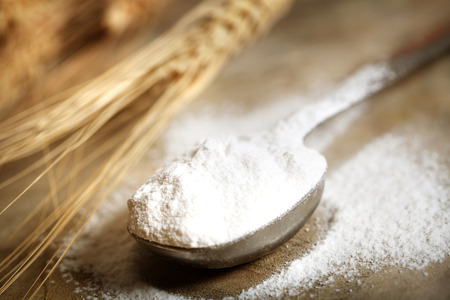 Wheat flour in measruing spoon on rustic wooden tableの写真素材