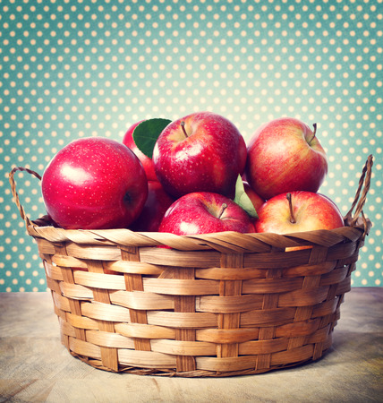 Red apples in basket over polka dots background in vintage styleの写真素材