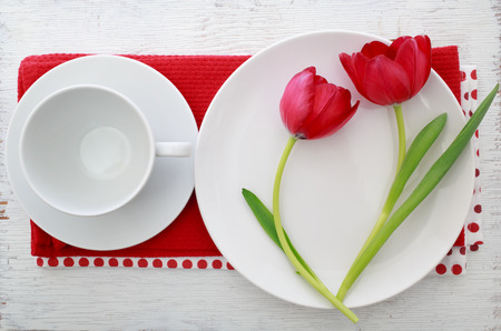 Red tulips with table set on red napkinsの写真素材
