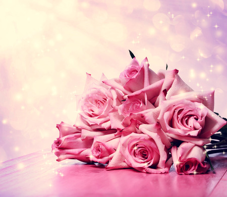 Beautiful pink roses on pink wooden table over shiny backgroundの写真素材