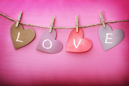 Love message on paper hearts over pink wooden boardの写真素材