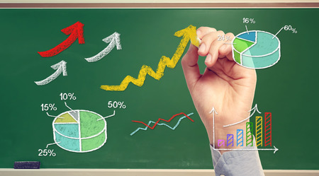 Hand drawing rising arrows and graphs on green chalk boardの写真素材