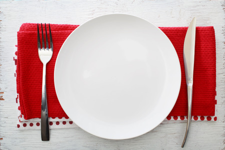 White plate with fork and knife on red napkinsの写真素材