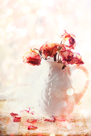 Dried pink roses in vase over shiny backgroundの写真素材