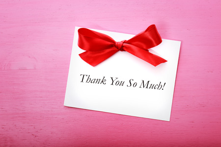 Thank you card with red ribbon on pink wooden boardの写真素材