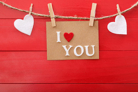 I Love You message card and felt hearts with clothespins over red wooden boardの写真素材