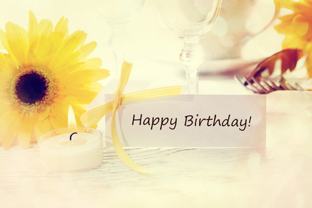 Birthday message card with table setting and yellow gerberasの写真素材
