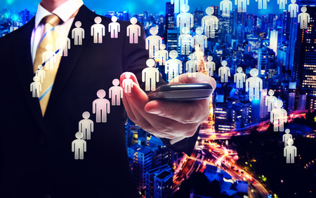 Business man holding a cellphone with human iconsの写真素材