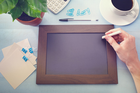 Blank chalkboard with green plant and office suppliesの写真素材