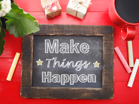 Make Things Happen message written on a vintage chalkboard on a red tableの写真素材