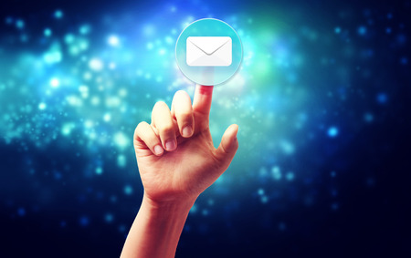 Hand pressing a envelope icon over technology blue backgroundの写真素材
