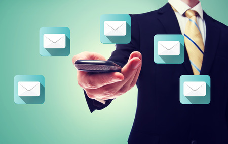 Businessman holding a cell phone with email iconsの写真素材