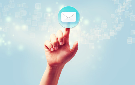 Hand pressing a envelope icon over light blue backgroundの写真素材