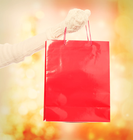 Woman holding red shopping bag over orange shiny backgroundの写真素材