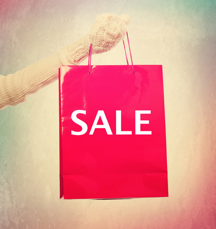 Woman with winter clothes holding Sale red shopping bagの写真素材