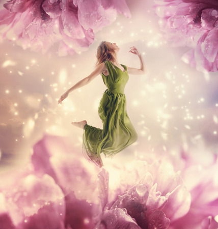 Beautiful young woman jumping on a giant flowerの写真素材